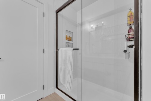 Shower with a clear glass enclosure and dark trim, featuring built-in shelving and overhead lighting - 9 Hunter Place, Spruce Grove, AB - Indoor Photo Showing Bathroom