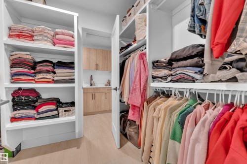 This property features an organized walk-in closet with extensive shelving, hanging rails, and light wood flooring - 9 Hunter Place, Spruce Grove, AB - Indoor With Storage