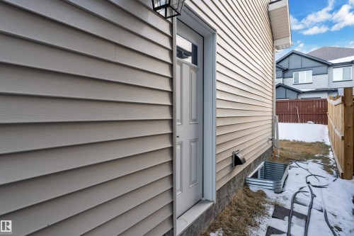 The property features horizontal siding on its exterior, a white panel door with a window, and a foundation visible at ground level - 9 Hunter Place, Spruce Grove, AB - Outdoor