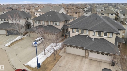The property features a dark grey shingle roof, light-colored siding, and stone accents on the garage - 2037 69A Street, Edmonton, AB - Outdoor