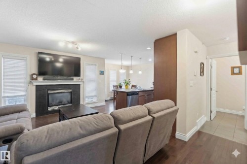 The living area features dark wood flooring, a fireplace with a dark surround, and two windows with blinds - 2037 69A Street, Edmonton, AB - Indoor Photo Showing Living Room With Fireplace