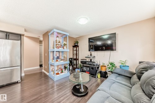 The living space features wood-style flooring, light-toned walls, and a ceiling light fixture - 23 445 Brintnell Boulevard Nw, Edmonton, AB - Indoor Photo Showing Living Room