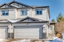 The property's exterior features light-colored siding, a dark roof, and a two-car garage with a stone accent facade - 23 445 Brintnell Boulevard Nw, Edmonton, AB  - Outdoor With Facade 