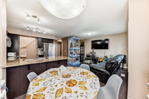 Open-concept living space featuring dark wood flooring, recessed lighting, and a kitchen with stainless steel appliances and a granite countertop - 23 445 Brintnell Boulevard Nw, Edmonton, AB - Indoor Photo Showing Other Room