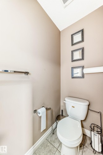 This powder room features neutral-toned walls, a white toilet, and tiled flooring - 23 445 Brintnell Boulevard Nw, Edmonton, AB - Indoor Photo Showing Bathroom