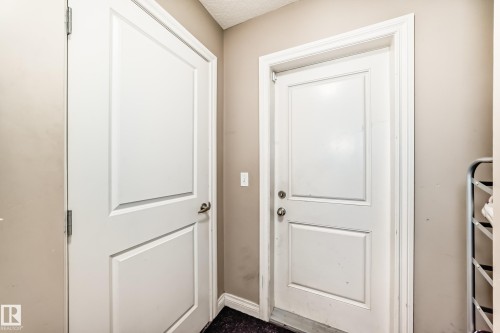 Entryway featuring two white panel doors and neutral-toned walls - 23 445 Brintnell Boulevard Nw, Edmonton, AB - Indoor Photo Showing Other Room