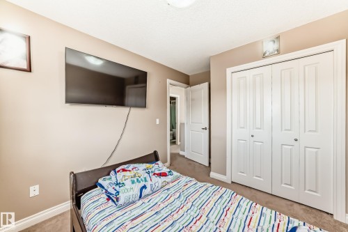 This room features neutral-toned walls, a textured ceiling, and carpeted flooring - 23 445 Brintnell Boulevard Nw, Edmonton, AB - Indoor Photo Showing Bedroom