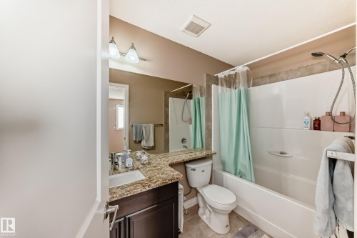 The bathroom features a vanity with a granite countertop and a white sink, an overhead light fixture, and a bathtub with a shower - 23 445 Brintnell Boulevard Nw, Edmonton, AB - Indoor Photo Showing Bathroom