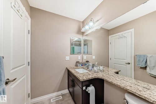 The bathroom features a vanity with a granite countertop, a single sink, and dark wood cabinetry - 23 445 Brintnell Boulevard Nw, Edmonton, AB - Indoor Photo Showing Bathroom