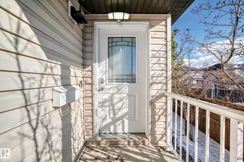 The property features a front entrance with a white door, decorative glass insert, and a porch light - 23 445 Brintnell Boulevard Nw, Edmonton, AB - Outdoor