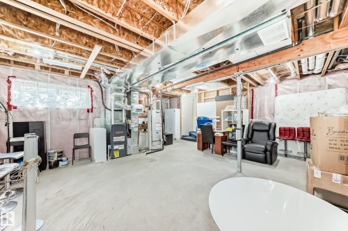 The unfinished basement offers an expansive open area with visible structural elements and utilities, including exposed ceiling joists, ductwork, and a furnace - 23 445 Brintnell Boulevard Nw, Edmonton, AB - Indoor Photo Showing Basement