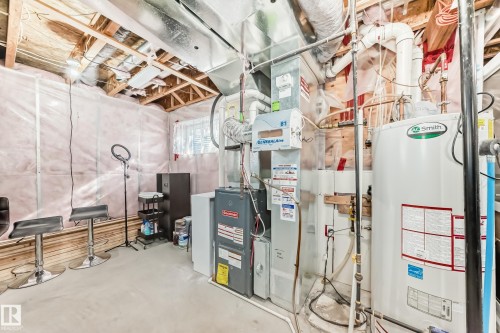 Utility area featuring a furnace, hot water heater, and exposed ceiling joists - 23 445 Brintnell Boulevard Nw, Edmonton, AB - Indoor Photo Showing Basement