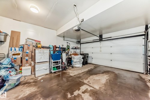 The property features a garage with a white overhead door and overhead lighting - 23 445 Brintnell Boulevard Nw, Edmonton, AB - Indoor Photo Showing Garage