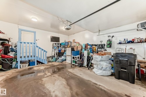 The property features a garage with a concrete floor, a white ceiling, and a blue painted stairway with a white door - 23 445 Brintnell Boulevard Nw, Edmonton, AB - Indoor Photo Showing Garage