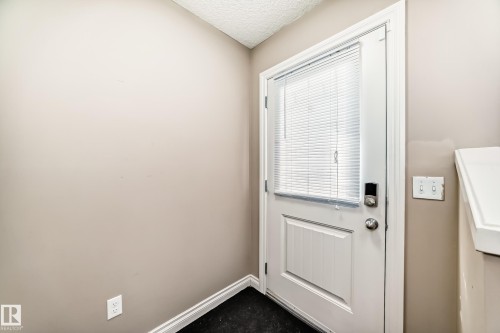 Entrance featuring a white door with a window and integrated blinds, a dark floor, and light-colored walls - 23 445 Brintnell Boulevard Nw, Edmonton, AB - Indoor Photo Showing Other Room
