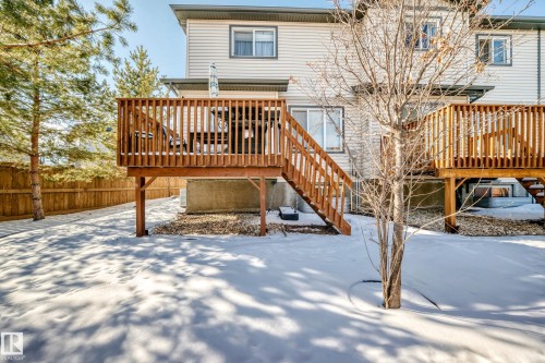 The property features a raised wooden deck with railings and stairs providing access to the yard - 23 445 Brintnell Boulevard Nw, Edmonton, AB - Outdoor