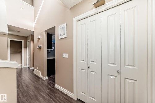 The property features neutral-toned walls, dark wood-style flooring, and white trim throughout the hallway - 23 445 Brintnell Boulevard Nw, Edmonton, AB - Indoor Photo Showing Other Room