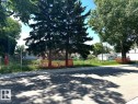 The property features mature trees, a clear parcel of land with visible fencing, and a paved road frontage with a sidewalk - 12072 95 Street, Edmonton, AB 