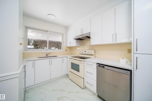 The kitchen features white cabinetry, a stainless steel dishwasher, and a window above the sink - 6411 149 Avenue Nw, Edmonton, AB - Indoor Photo Showing Kitchen With Double Sink