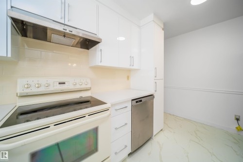 The kitchen features white cabinetry, a stainless steel range hood, a white electric stove, and a stainless steel dishwasher - 6411 149 Avenue Nw, Edmonton, AB - Indoor Photo Showing Kitchen