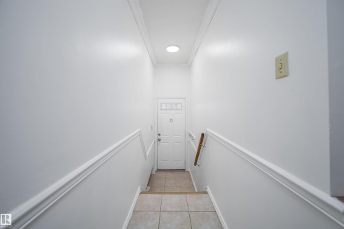 The property features a white paneled door with glass inserts, a wooden handrail, and white walls with decorative trim - 6411 149 Avenue Nw, Edmonton, AB - Indoor Photo Showing Other Room