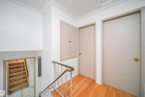 The property features hardwood flooring and a staircase with a white and brass railing - 6411 149 Avenue Nw, Edmonton, AB - Indoor Photo Showing Other Room