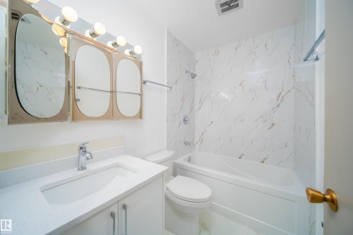 Bathroom featuring a vanity with a white countertop and an integrated sink, a toilet, and a bathtub with a shower - 6411 149 Avenue Nw, Edmonton, AB - Indoor Photo Showing Bathroom