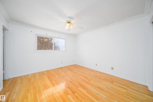This room features hardwood floors, a white ceiling fan with integrated lighting, and a window providing natural light - 6411 149 Avenue Nw, Edmonton, AB - Indoor Photo Showing Other Room