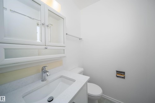 Bathroom featuring a white vanity with a rectangular sink, a chrome faucet, and a wall-mounted medicine cabinet with mirrored doors - 6411 149 Avenue Nw, Edmonton, AB - Indoor Photo Showing Bathroom
