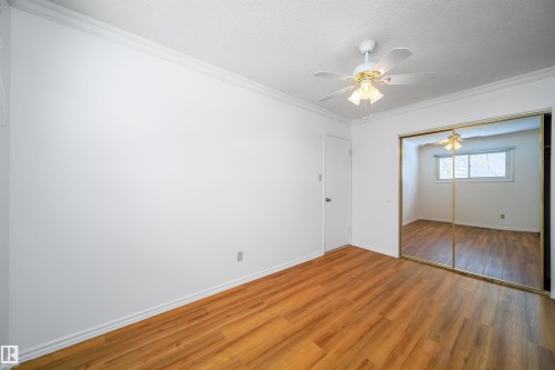 This room features rich wood flooring, crown molding, and a ceiling fan with integrated lighting - 6411 149 Avenue Nw, Edmonton, AB - Indoor Photo Showing Other Room