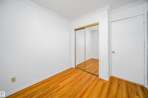 This room features warm-toned wood flooring, white walls, and crown molding - 6411 149 Avenue Nw, Edmonton, AB - Indoor Photo Showing Other Room