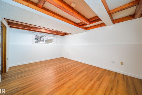 Spacious room featuring exposed wooden beams, a window, and wood-toned flooring - 6411 149 Avenue Nw, Edmonton, AB - Indoor Photo Showing Other Room