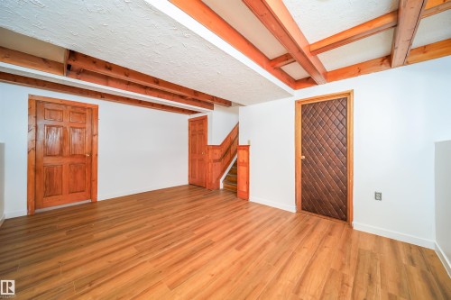 Spacious room featuring exposed wooden ceiling beams and light wood-style flooring - 6411 149 Avenue Nw, Edmonton, AB - Indoor Photo Showing Other Room