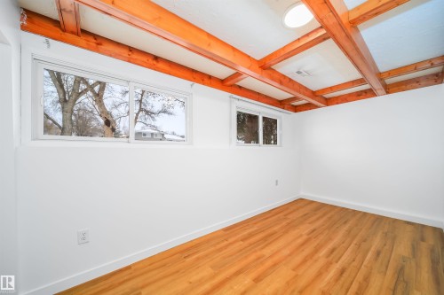 This room features exposed wooden beams, durable laminate flooring, and bright white walls - 6411 149 Avenue Nw, Edmonton, AB - Indoor Photo Showing Other Room
