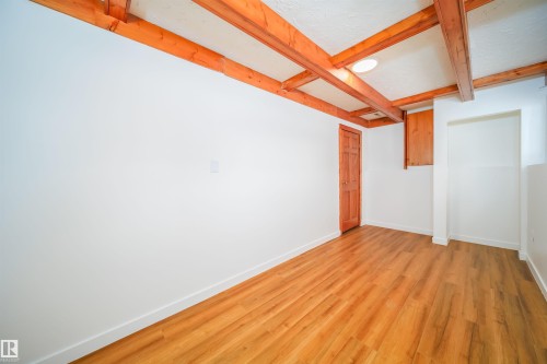 This room features exposed wooden ceiling beams and light wood-tone flooring, complemented by white walls - 6411 149 Avenue Nw, Edmonton, AB - Indoor Photo Showing Other Room