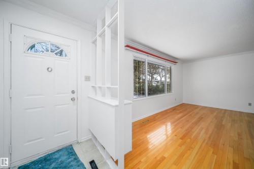The property features a bright entryway with a white door, a decorative arched window, and a built-in storage unit - 6411 149 Avenue Nw, Edmonton, AB - Indoor Photo Showing Other Room