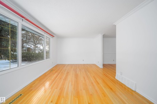 Spacious room featuring light wood flooring, white walls, and large windows with clear views of exterior trees and snow - 6411 149 Avenue Nw, Edmonton, AB - Indoor Photo Showing Other Room