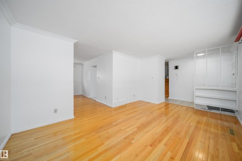 This living space features hardwood flooring, white walls, and crown molding - 6411 149 Avenue Nw, Edmonton, AB - Indoor Photo Showing Other Room