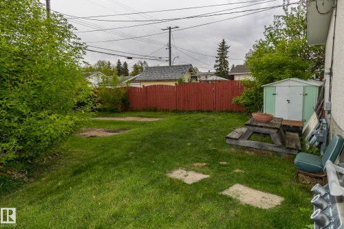 The property features a spacious backyard with a well-maintained lawn and a red wooden fence - 10512 55 Avenue, Edmonton, AB - Outdoor