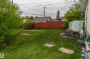 The property features a spacious backyard with a well-maintained lawn and a red wooden fence - 10512 55 Avenue, Edmonton, AB  - Outdoor 
