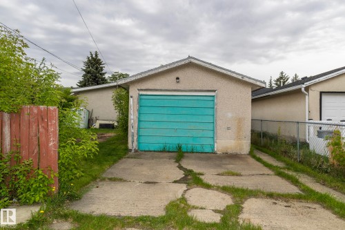 Detached garage with a turquoise door, concrete driveway, and a chain link fence - 10512 55 Avenue, Edmonton, AB - Outdoor