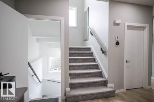 The interior features a carpeted staircase with a handrail, light-colored walls, and a window providing natural light - 266 Charlesworth Drive, Edmonton, AB - Indoor Photo Showing Other Room
