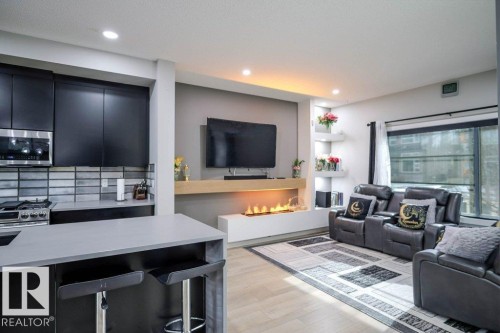 The living area features light wood flooring, a fireplace, and a large window - 266 Charlesworth Drive, Edmonton, AB - Indoor Photo Showing Living Room