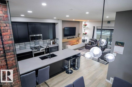 Open concept living area featuring a kitchen island with seating, dark cabinetry, and light-colored countertops - 266 Charlesworth Drive, Edmonton, AB - Indoor Photo Showing Kitchen With Double Sink With Upgraded Kitchen