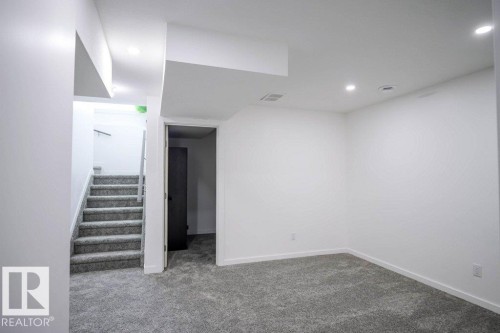 This versatile room features plush gray carpeting, recessed lighting, and crisp white walls, offering a blank canvas for personalization - 266 Charlesworth Drive, Edmonton, AB - Indoor Photo Showing Other Room