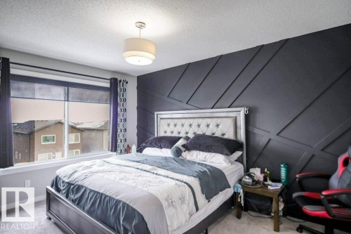 The room features a decorative accent wall with geometric paneling and a ceiling-mounted light fixture - 266 Charlesworth Drive, Edmonton, AB - Indoor Photo Showing Bedroom