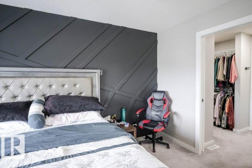 Bedroom featuring a dark accent wall with decorative paneling and an open doorway leading to a walk-in closet with shelving and hanging space - 266 Charlesworth Drive, Edmonton, AB - Indoor Photo Showing Bedroom
