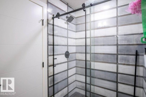 Shower featuring a glass enclosure with matte black hardware, a matte black rain showerhead, and subway tile walls in varying shades of grey and white - 266 Charlesworth Drive, Edmonton, AB - Indoor