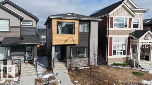 The property features a contemporary exterior with a combination of light wood-tone and dark siding, complemented by stone accents on the lower level - 266 Charlesworth Drive, Edmonton, AB - Outdoor With Facade