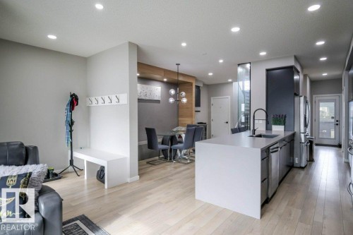 The property features light-colored flooring throughout, a modern kitchen island with an integrated sink and faucet, and recessed lighting - 266 Charlesworth Drive, Edmonton, AB - Indoor Photo Showing Kitchen With Upgraded Kitchen